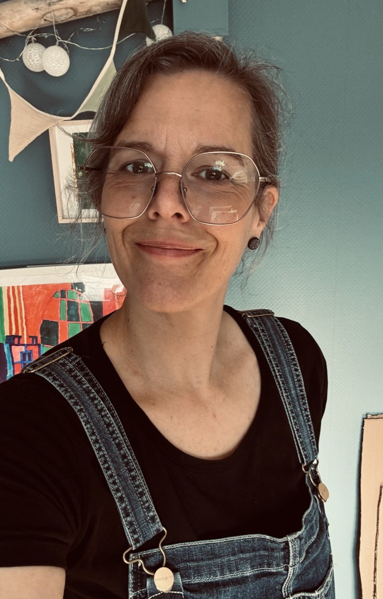 Katrin Krämer-Micklisch lächelt vor einer Wand mit Bildern.